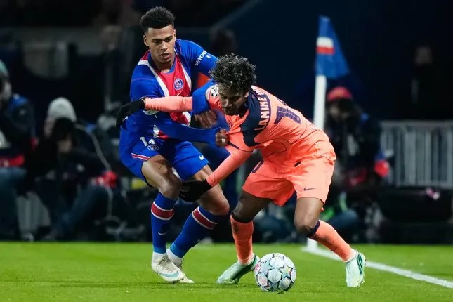 Pemain Barcelona Lamine Yamal mendapat kawalan dari pemain PSG Desire Doue dalam pertandingan Liga Champions, Rabu (21/10/2026). (c) AP Photo/Teresa Suarez